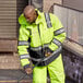 A man wearing a Cordova Hi-Vis Lime yellow parka cleaning the sidewalk.