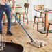 A man using a Lavex blue fiberglass mop handle to mop a floor.