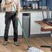 A man using a Lavex metal mop handle to clean the floor in a professional kitchen.