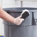 A hand holding a Choice black nylon utility brush cleaning a bucket.