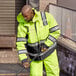 A man wearing a Cordova Hi-Vis lime yellow quilted parka with a black pole.