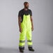 A man wearing Cordova hi-vis lime yellow quilted bib pants with chest pockets.