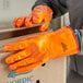 A person wearing Cordova orange warehouse gloves opening a box.