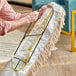 A person using a Lavex swivel snap wire dust mop frame to clean a rug.