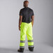 A man wearing Cordova Hi-Vis lime yellow quilted bib pants over a black shirt.