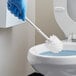 A hand in blue gloves using a Lavex white toilet bowl brush to clean a toilet.