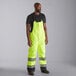 A man wearing Cordova Hi-Vis Lime yellow quilted bib pants.