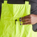 A person holding a tool in a pocket on Cordova hi-vis lime quilted bib pants.