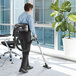 A man using an Atrix Ergo Lite hip vacuum cleaner to vacuum a room.