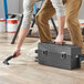 A person using an Atrix Omega Plus abatement vacuum to clean a wood floor.