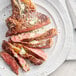 A plate of steak with Urbani White Truffle Butter and green onions on a white surface.