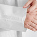 A person's hands touching a white disposable lab coat in a bag.
