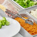 A person in a plastic glove using a Choice Round Stainless Steel Squeeze Handle Disher to serve rice over a plate of broccoli.