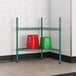 A green metal shelf with red buckets on it.