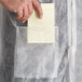 A person wearing a white Malt Impact PolyLite lab coat holding a note pad.