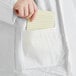A person holding a note in the pocket of a white Malt Impact ProMax lab coat.