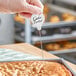 A hand holding a piece of cake with a Choice 7 5/8" Cake Tester in the middle.