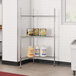 A Regency chrome wire triangle shelf kit in a school kitchen with cans of food on it.