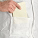 A hand holding a note in the pocket of a white lab coat.