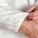 A person's hands buttoning a white Malt Impact ProMax lab coat.