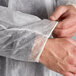 A person wearing a white polypropylene lab coat with elastic wrists.