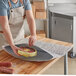 A person wearing an apron uses a Lavex insulated foil bubble mailer to hold a round yellow food item.