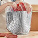 A woman holding a Lavex Pro heavy-duty insulated box liner filled with meat.