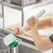 A person cleaning a pot with a green Lavex utility brush.