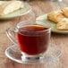 A glass cup of Ellis Mezzaroma French Caramel Creme coffee on a plate with pastries.