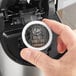 A hand placing a white Ellis Mezzaroma Royal Sumatra coffee pod in a coffee machine.