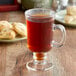 A glass cup of brown Ellis Mezzaroma Salted Caramel coffee on a table with cookies.