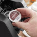 A hand holding a round white and brown label on a box of Ellis French Vanilla Brulee Coffee Single Serve Cups.