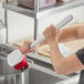 A woman using a red Lavex pot scrub brush to clean a pot.