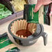A person pouring Ellis Mezzaroma medium roast coffee into a coffee filter.
