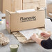 A woman using Ranpak Geami WrapPak to pack a box.