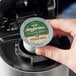 A hand holding an Ellis Mezzaroma Costa Rican Tarrazu coffee capsule over a coffee maker.