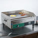 A Waring countertop electric griddle with eggs and bacon cooking on it.