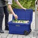 A man putting bottles into a CaterGator navy outdoor cooler.