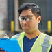 A man wearing Honeywell safety reader glasses and a safety vest holding a clipboard.