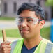 A man wearing Honeywell Uvex safety glasses and a reflective vest while using a hammer.