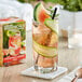 A glass of water with a cucumber slice and a slice of watermelon on the rim.