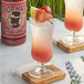 A glass of pink liquid with a slice of grapefruit on top of it with a Top Hat Provisions Ruby Go Wild Paloma 5:1 Concentrate label.