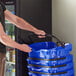 A man holding a stack of Regency Blue plastic grocery market shopping baskets.