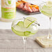A glass of Top Hat Provisions sugar-free margarita mix with a lime wedge.