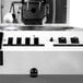 A close-up of a Primo RAVEN-Xr15 white coffee roaster.