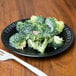 A Dart black laminated foam plate with a piece of broccoli on it and a fork.