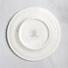 A white RAK Porcelain flat plate with an embossed circular design.