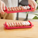 Two people holding red Controltek USA coin trays filled with pennies.