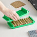 A hand holding a green plastic coin tray filled with dimes.