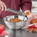 A person using a Choice stainless steel mixing bowl to put food on a table.